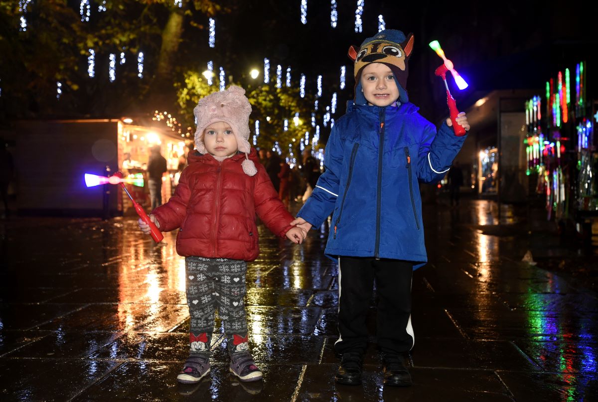 Children holding hands enjoying Christmas lights